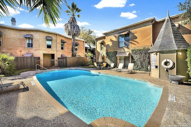 pool with a patio and fence