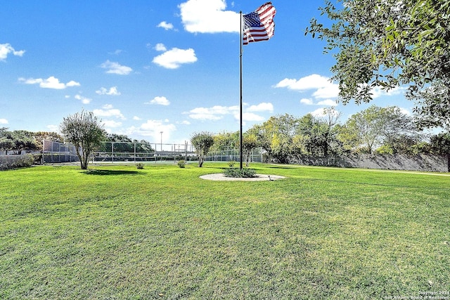 view of property's community with fence and a lawn