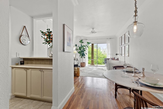 dining space with ceiling fan, baseboards, light wood-style floors, and a textured wall