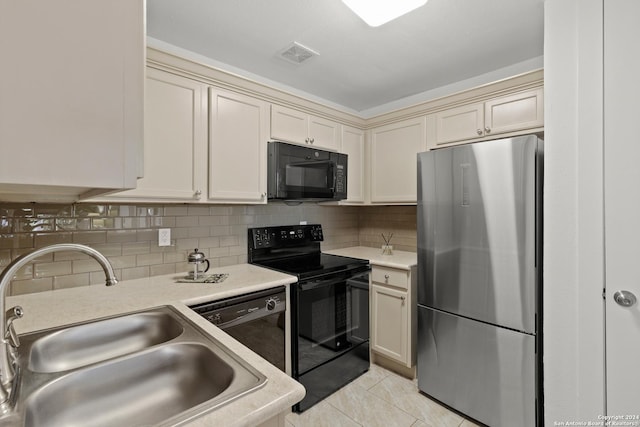 kitchen with visible vents, black appliances, a sink, light tile patterned floors, and decorative backsplash