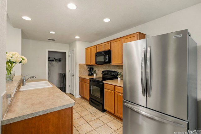 kitchen with backsplash, sink, light tile patterned flooring, and black appliances