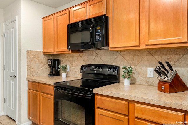 kitchen featuring black appliances, light tile patterned floors, and backsplash