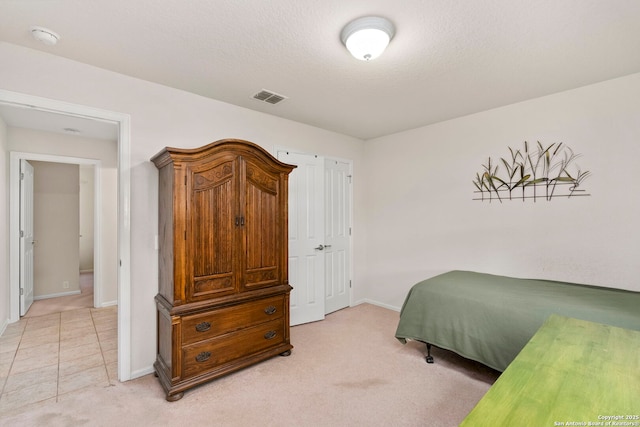 bedroom featuring light colored carpet and a textured ceiling