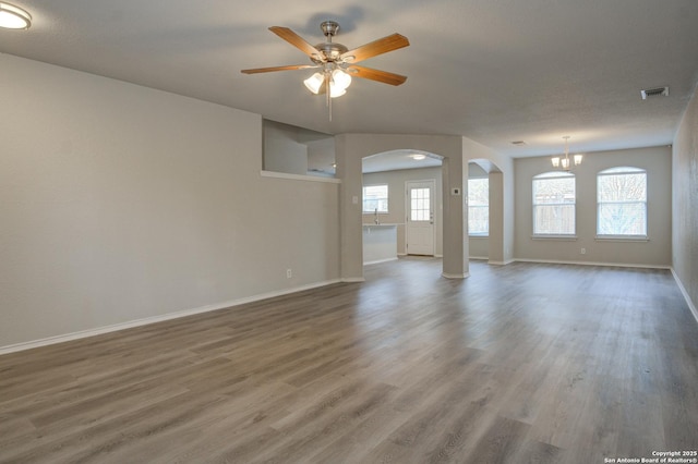 spare room featuring wood-type flooring and ceiling fan with notable chandelier