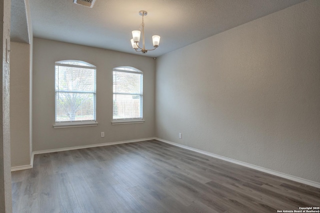 empty room featuring dark hardwood / wood-style floors and an inviting chandelier