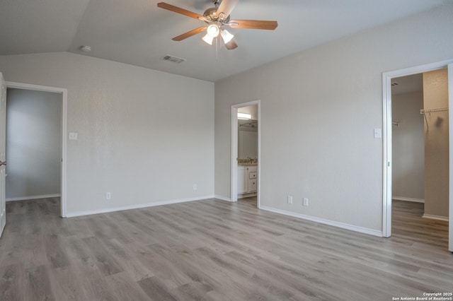 unfurnished bedroom with a spacious closet, ceiling fan, light hardwood / wood-style flooring, ensuite bathroom, and a closet