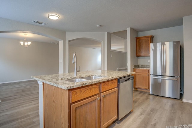 kitchen with sink, stainless steel appliances, a notable chandelier, pendant lighting, and a center island with sink