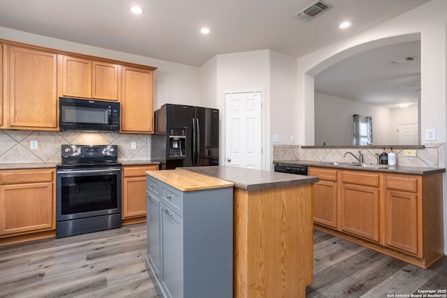 kitchen with tasteful backsplash, sink, black appliances, light hardwood / wood-style flooring, and a kitchen island