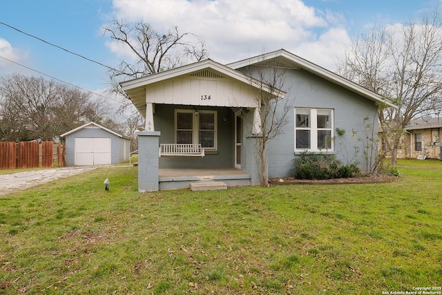 bungalow-style house with a front yard, a porch, and an outbuilding