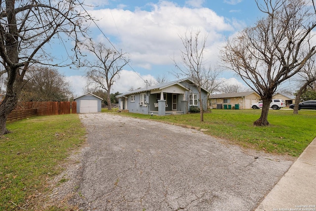 view of front of house featuring a porch, a garage, a front lawn, and an outdoor structure