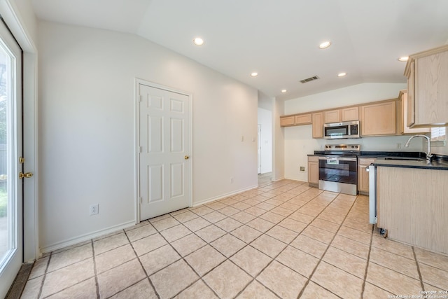 kitchen featuring lofted ceiling, sink, light brown cabinetry, appliances with stainless steel finishes, and light tile patterned flooring