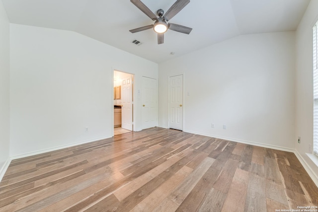 unfurnished bedroom with ensuite bathroom, ceiling fan, vaulted ceiling, and hardwood / wood-style flooring