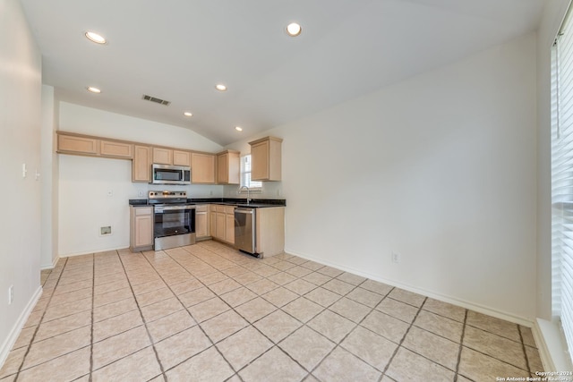 kitchen with light brown cabinets, sink, vaulted ceiling, light tile patterned floors, and appliances with stainless steel finishes