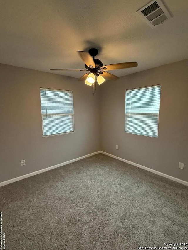 empty room with plenty of natural light, ceiling fan, and carpet floors