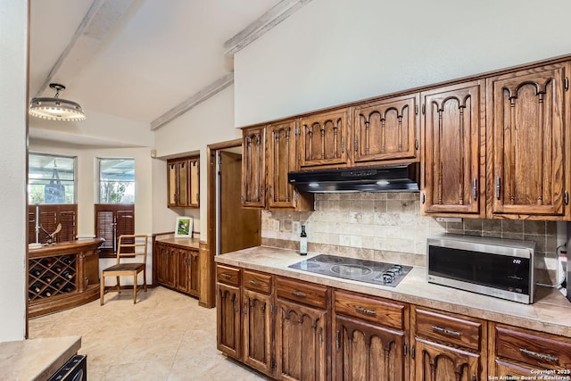 kitchen featuring lofted ceiling, light tile patterned floors, tasteful backsplash, and cooktop