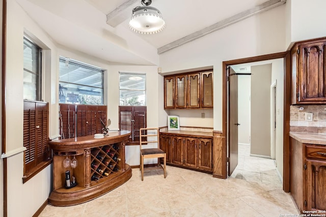 kitchen featuring lofted ceiling, light tile patterned flooring, and tasteful backsplash