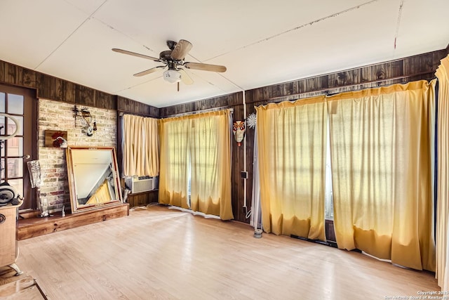 interior space with wood-type flooring, wooden walls, and ceiling fan