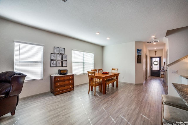 dining space featuring a textured ceiling and light hardwood / wood-style floors