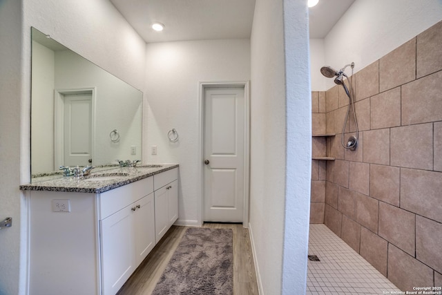 bathroom with tiled shower, vanity, and hardwood / wood-style flooring