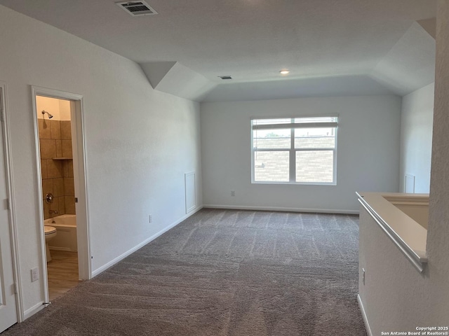 carpeted spare room featuring vaulted ceiling