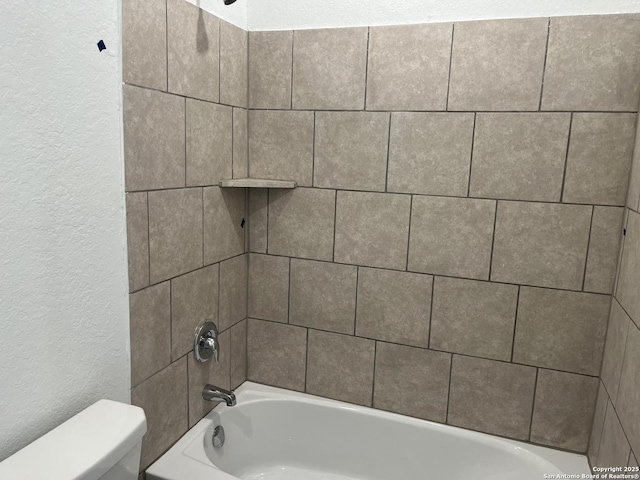 bathroom featuring toilet and tiled shower / bath