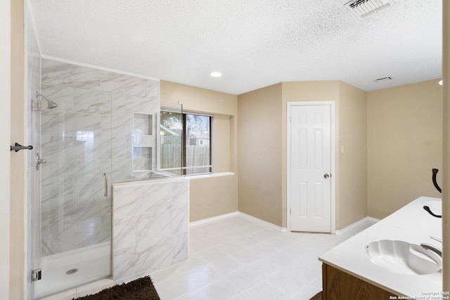 bathroom with vanity, a shower with shower door, and a textured ceiling