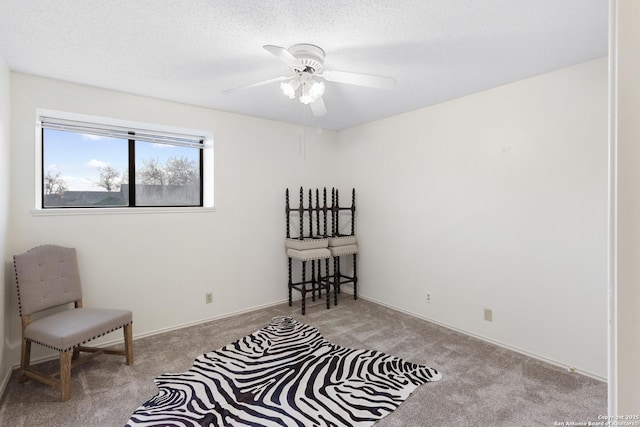 living area with ceiling fan, light carpet, and a textured ceiling