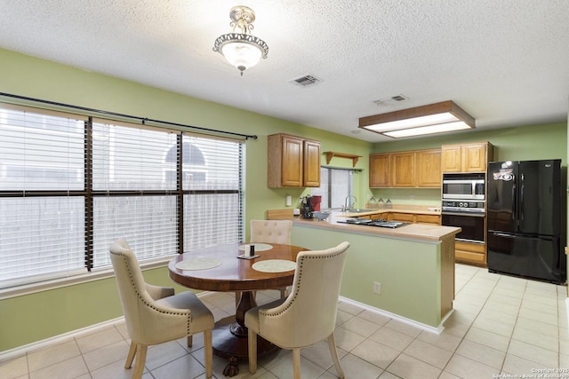 kitchen featuring a kitchen island, sink, light tile patterned floors, black appliances, and a textured ceiling