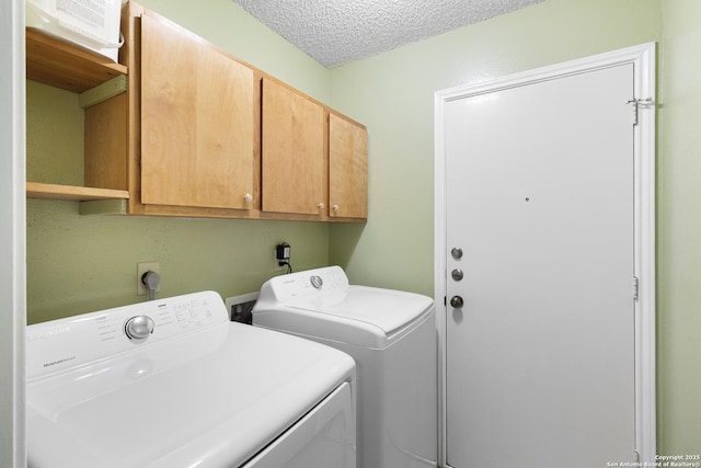 washroom featuring cabinets, washing machine and dryer, and a textured ceiling