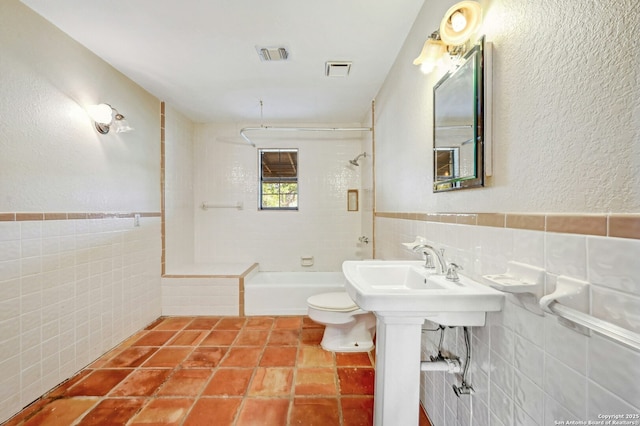 full bathroom featuring sink, tiled shower / bath, tile walls, and toilet