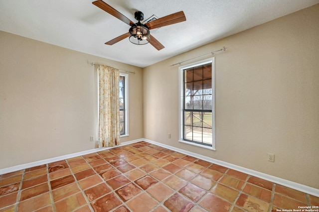 tiled empty room with ceiling fan and a healthy amount of sunlight