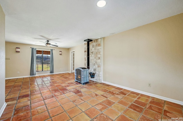 unfurnished living room with a wood stove, ceiling fan, and tile patterned flooring