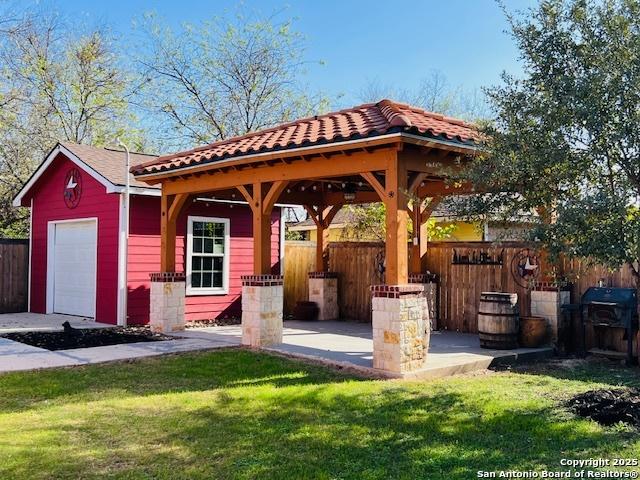 view of patio / terrace with a gazebo, a garage, and an outbuilding