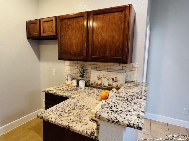 kitchen featuring backsplash, light stone counters, and light tile patterned floors