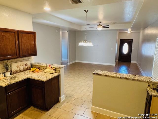 kitchen featuring kitchen peninsula, a tray ceiling, hanging light fixtures, and ceiling fan