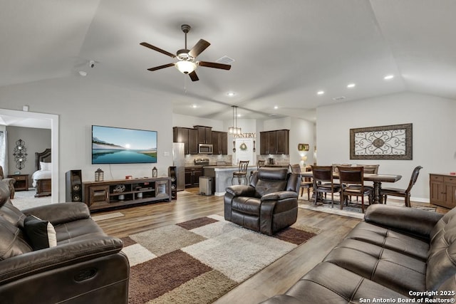 living room featuring ceiling fan, light wood-type flooring, and lofted ceiling