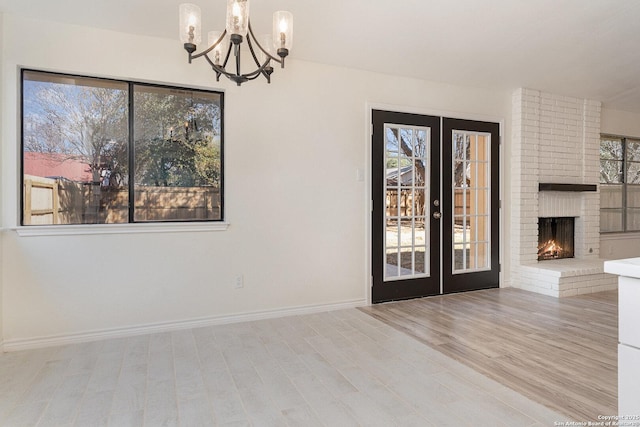 unfurnished room featuring a fireplace, french doors, and a notable chandelier