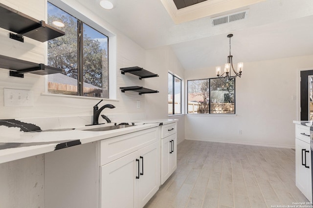 kitchen with pendant lighting, sink, light wood-type flooring, a notable chandelier, and white cabinetry