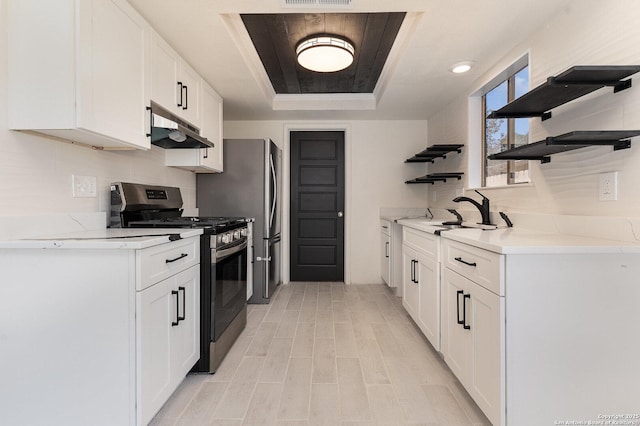 kitchen with a raised ceiling, sink, stainless steel gas range, tasteful backsplash, and white cabinetry