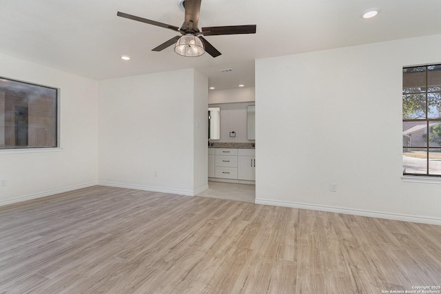 empty room with ceiling fan and light hardwood / wood-style flooring