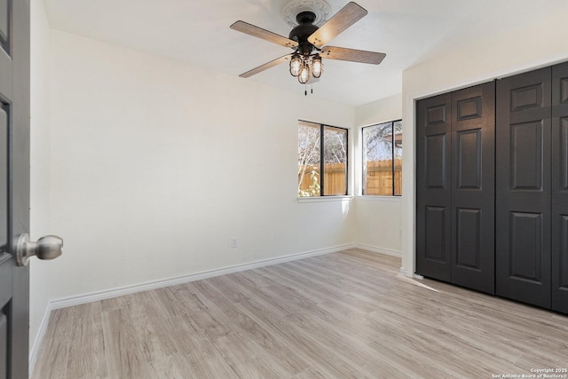 unfurnished bedroom featuring ceiling fan, a closet, and light wood-type flooring