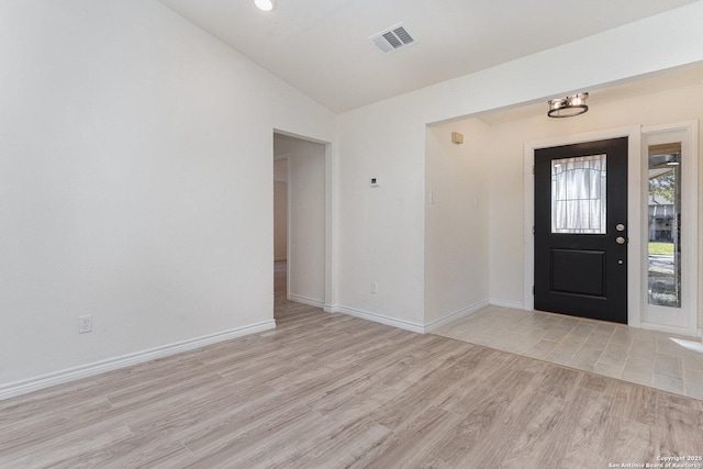 foyer entrance with a notable chandelier, light wood-type flooring, and vaulted ceiling