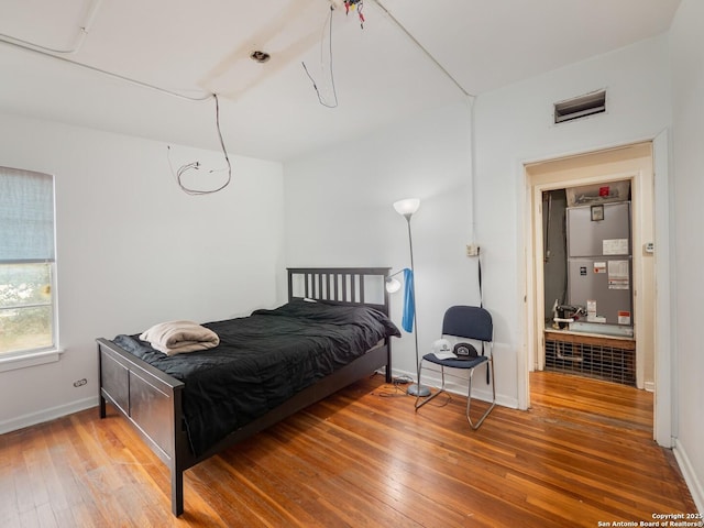 bedroom with hardwood / wood-style floors and heating unit