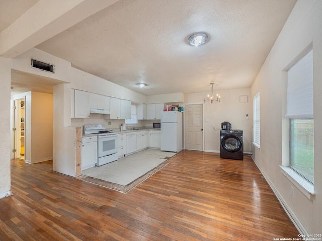 kitchen with white cabinetry, hardwood / wood-style floors, a chandelier, white appliances, and washer / dryer