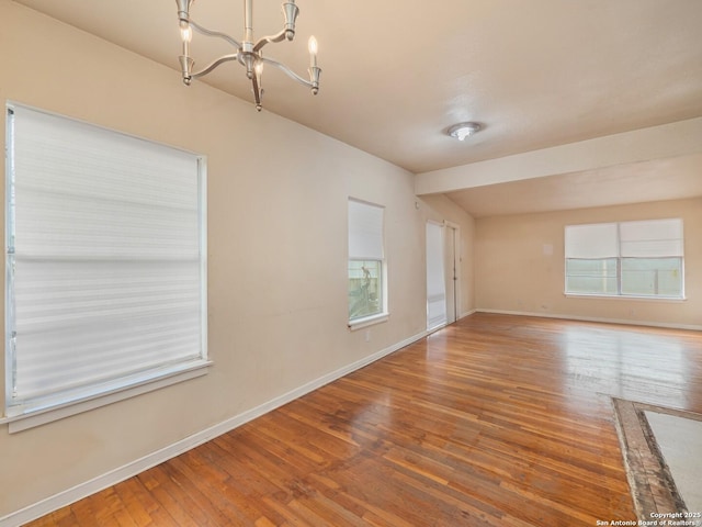 empty room with a notable chandelier and hardwood / wood-style flooring