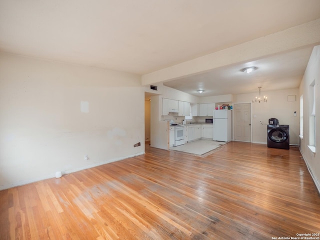 unfurnished living room featuring washer / dryer, light hardwood / wood-style flooring, and an inviting chandelier