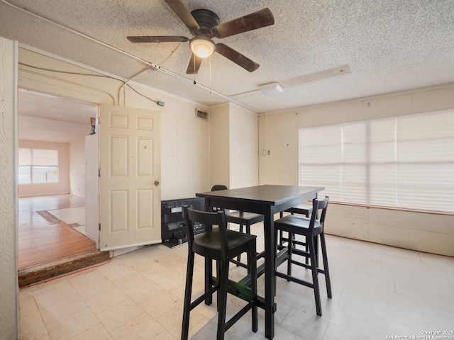 dining area featuring ceiling fan and a textured ceiling