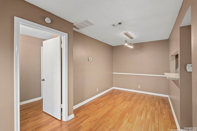 unfurnished room featuring wood-type flooring and a textured ceiling