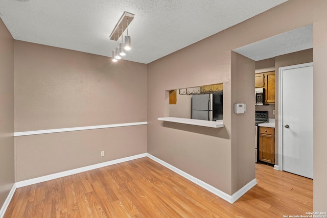 spare room with light hardwood / wood-style floors and a textured ceiling