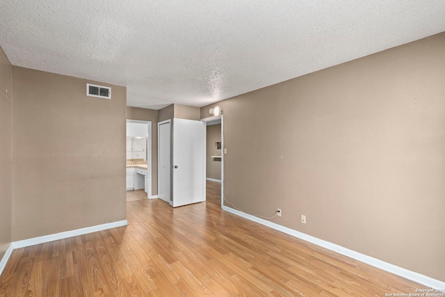 unfurnished room with a textured ceiling and light hardwood / wood-style flooring